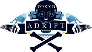 A navy and light blue logo of a skull and crossbones. Within the eyes of the skull are the kanji for Tokyo in white. The skull is flanked by light blue flowers. Past the flowers, there is a salmon with legs on either side of the logo. The word "TOKYO" is written in white across the forehead of the skull and the word "ADRIFT" is written across a banner in the jaws of the skull.